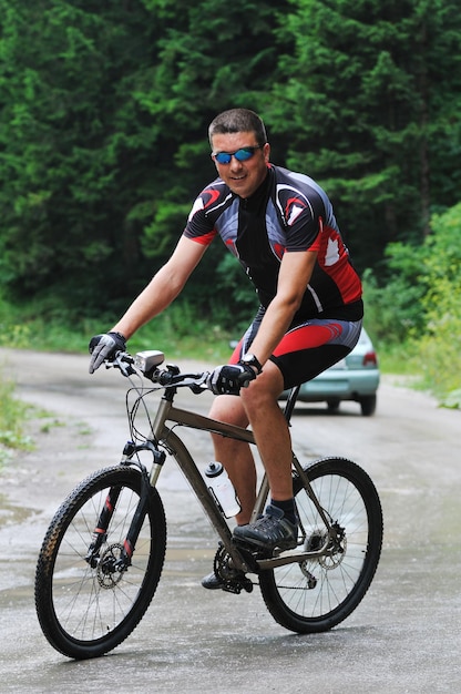 estilo de vida saudável e conceito de fitness com homem de bicicleta de montagem ao ar livre