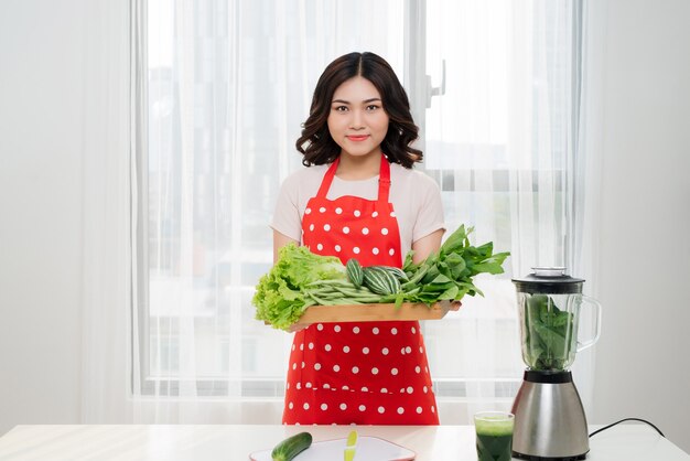 Estilo de vida saudável. Feliz sorrindo na cozinha para casa com vegetais verdes cozinhando