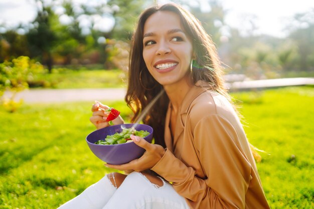 Estilo de vida saudável Mulher jovem comendo salada de vegetais frescos em um dia ensolarado ao ar livre Vegetariana