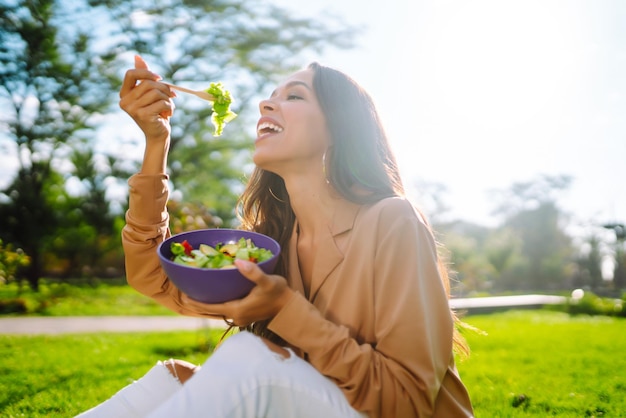 Estilo de vida saudável Mulher jovem comendo salada de vegetais frescos em um dia ensolarado ao ar livre Vegetariana