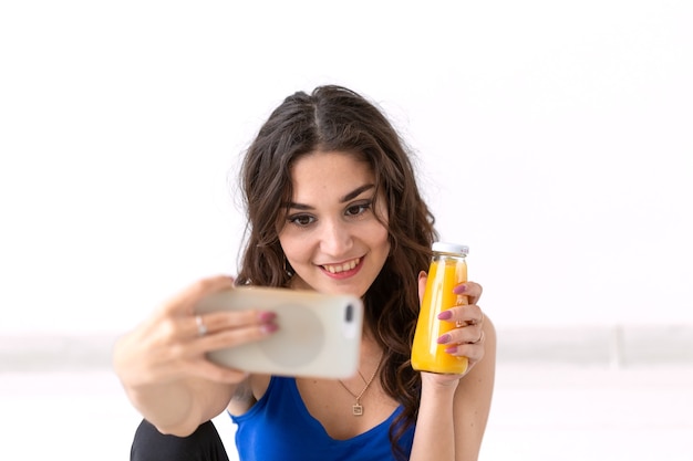 Estilo de vida saudável, pessoas e conceito de esporte - mulher tomando selfie e segurando suco