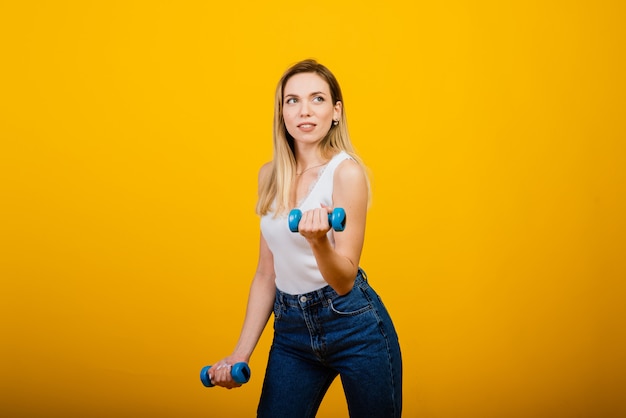 Estilo de vida saudável: retrato de corpo inteiro de uma jovem sorridente fitness em perfeita forma, foto do estúdio, parede amarela