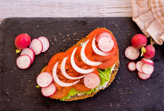 Estilo de vida saudável, sanduíche bio dietético com tomate, cebola e queijo de alface - alimentação leve e saborosa - pão integral com sementes