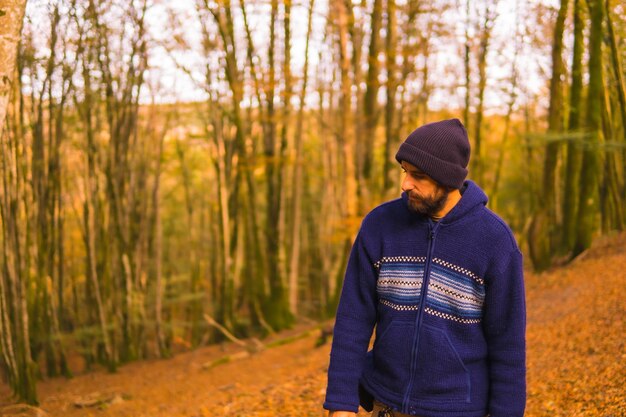 Estilo de vida um jovem em um suéter de lã azul e um chapéu curtindo a floresta