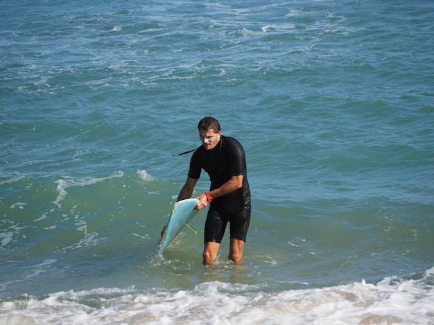 Estilo de vida. Um surfista cansado sai da água. Com a prancha de surf.