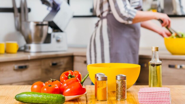 Estilo de vida vegan Closeup de vegetais orgânicos frescos azeite e especiarias na mesa da cozinha Mulher preparando salada