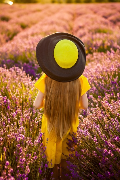 Estilo de vida. vista traseira. campo de lavanda. A garota do chapéu vai para o campo de flores. Liberdade, união com a natureza