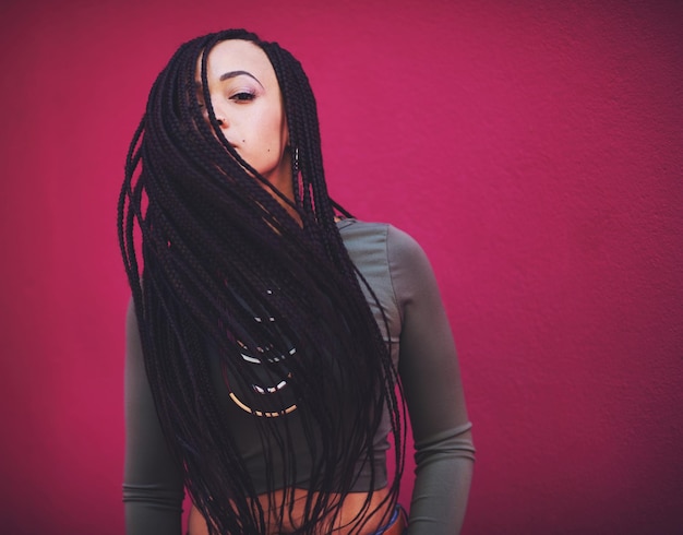 El estilo es el arte de ser uno mismo Foto de una mujer joven con trenzas posando sobre un fondo rosa