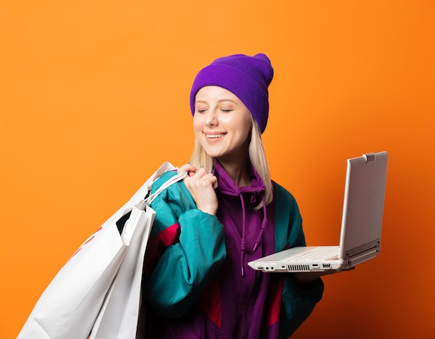 Estilo feminino com agasalho de treino dos anos 90 com caderno e sacolas de compras laranja