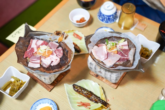 Estilo japonés de cerdo a la parrilla en la estufa tradicional con hojas secas locales y aperitivo alrededor.