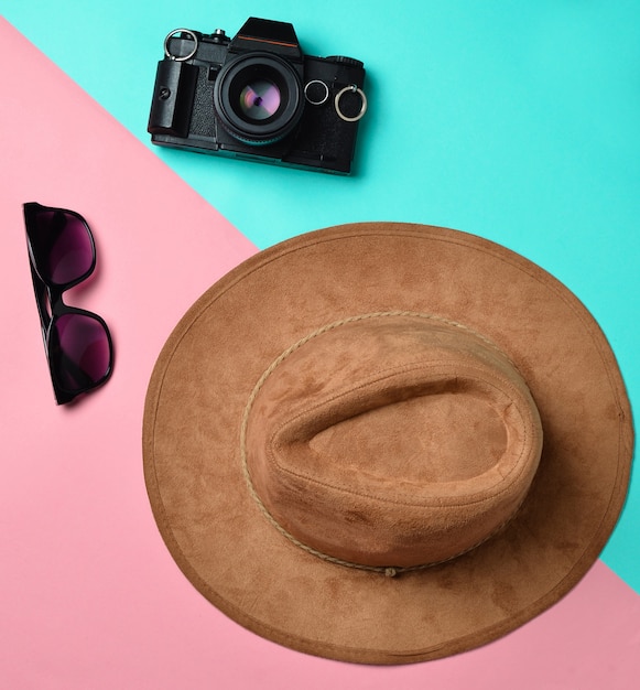 Estilo de moda creativo plano con cámara, gafas de sol y sombrero de fieltro sobre fondo de color pastel, pasión por los viajes.