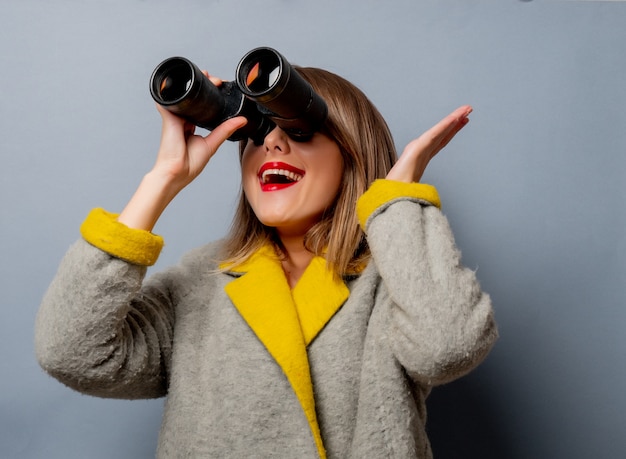 Estilo mujer en abrigo con binoculares