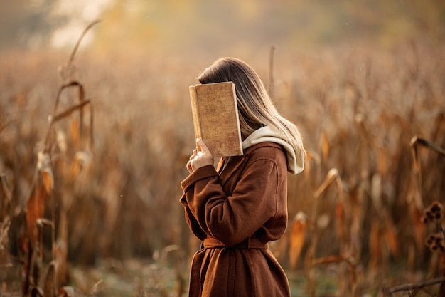 Foto estilo mulher com livro no campo de milho na temporada de outono