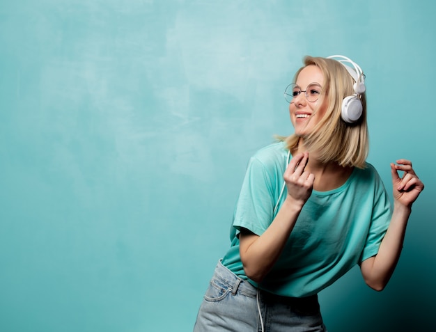 Estilo mulher loira de óculos com fones de ouvido está dançando