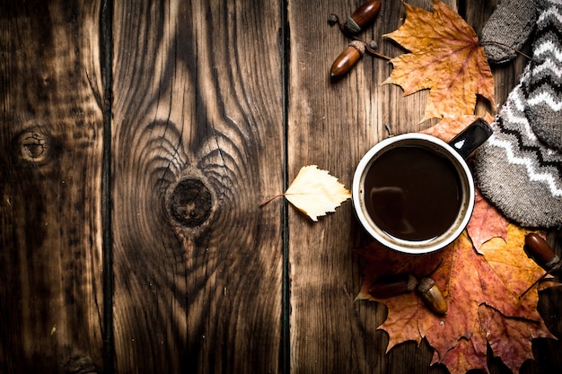 Estilo otoñal Una taza de café caliente con guantes sobre una mesa de madera