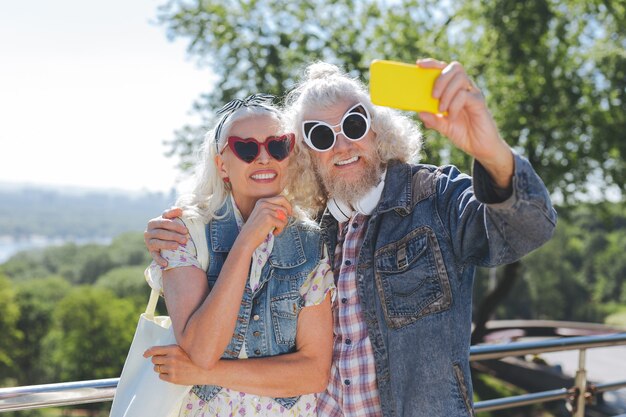 Estilo perfecto. Personas ancianas encantadas con gafas de sol mientras posan juntos para la foto