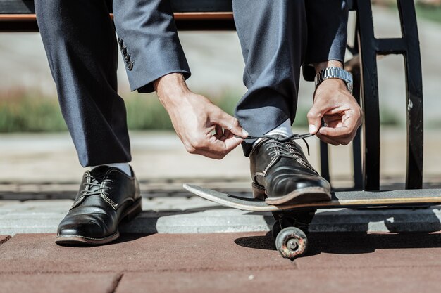 Estilo perfeito. Close-up de delicadas mãos masculinas amarrando cadarços e se preparando para andar de skate