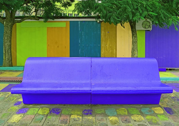 Estilo pop art vivo azul cobalto banco de hormigón vacío con paredes de madera multicolor en segundo plano.