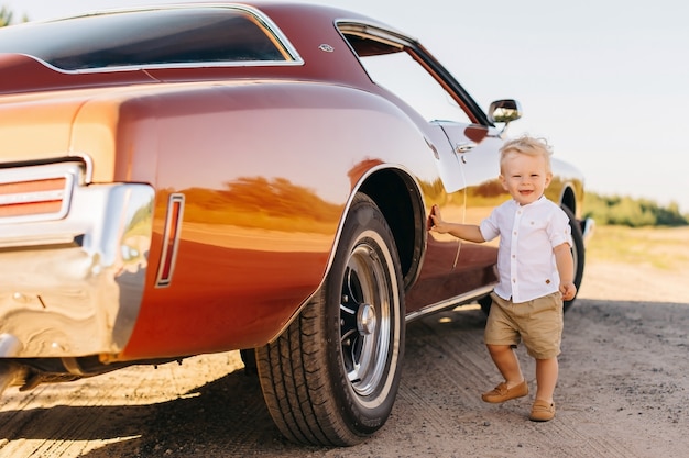 Estilo retrô buick rivierin. carro único. bonito rapaz loiro fica perto de carro retrô.