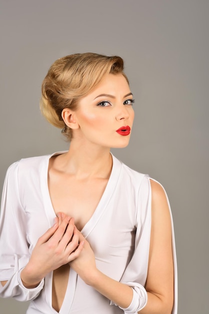 Estilo retro de mujer de moda elegante. Hermosa chica con piel limpia fresca perfecta, labios rojos, pestañas largas, maquillaje brillante, peinado retro. Sensual modelo rubia en vestido blanco que sopla beso.