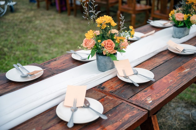 Estilo rústico de boda, mesa de comedor de madera con decoración de flores y vajilla