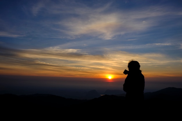 Estilo de silueta Hermosa chica encantadora de pie café y disfrutar de la vista la belleza de la naturaleza. Durante las horas del amanecer de la mañana, Gold Mountain View y la belleza desde un ángulo alto.