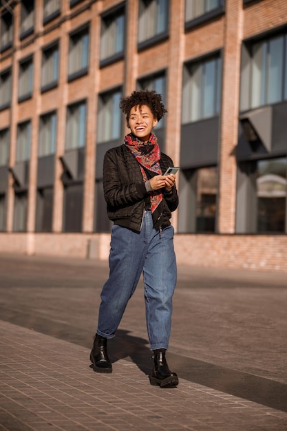 Estilo urbano. Chica joven de pelo oscuro en chaqueta y jeans en la calle