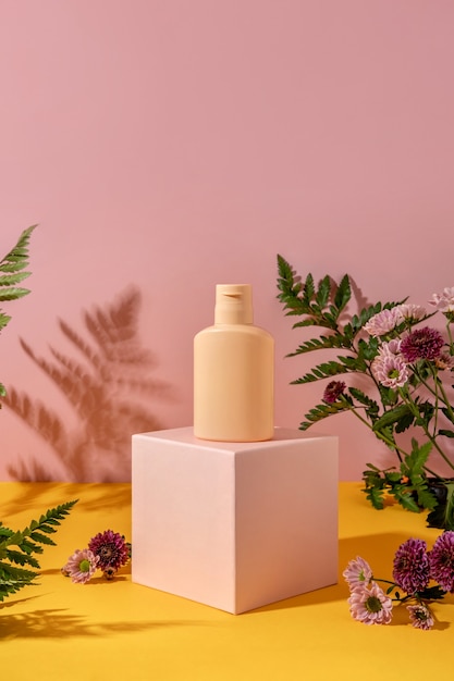 Estilo de verano de escaparate para exhibición de productos cosméticos sobre fondo amarillo y rosa. Botella de producto cosmético en un podio rosa.