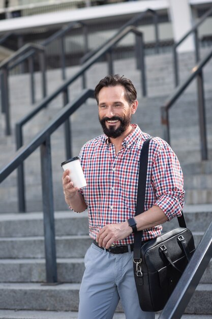 Estilo de vida activo. Alegre empresario barbudo caminando en la ciudad mientras expresa alegría