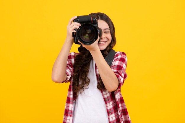 Estilo de vida adolescente hipster adolescente mantenga cámara profesional Chica con cámara de fotos fotografiando aislado sobre fondo de estudio Adolescente feliz emociones positivas y sonrientes de chica adolescente