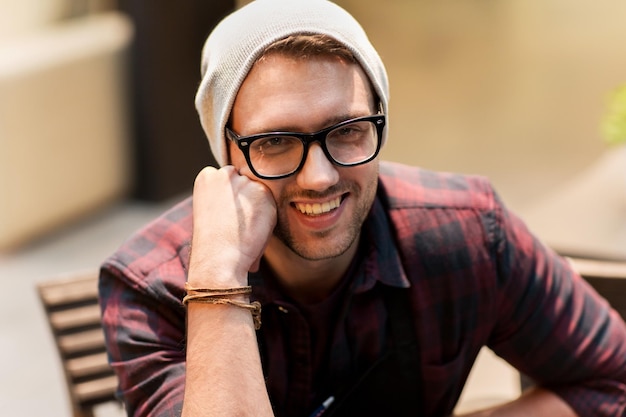 estilo de vida y concepto de la gente - hombre sonriente feliz con anteojos y sombrero hipster en el café
