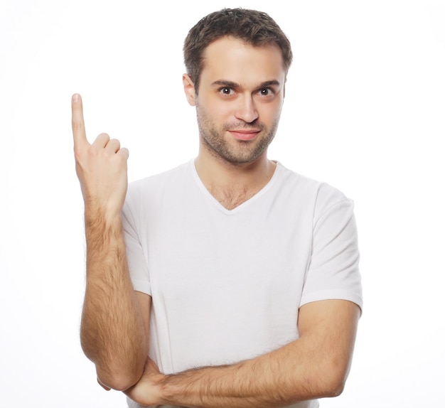 Estilo de vida y concepto de la gente: Joven hombre feliz sonriente muestra algo sobre fondo blanco.