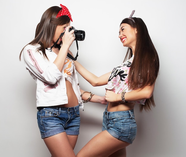 Estilo de vida y concepto de personas Felices amigas tomando algunas fotos con la cámara sobre fondo blanco.