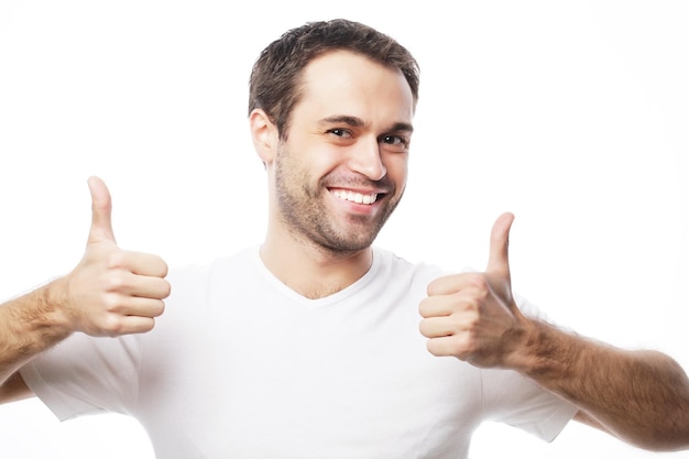 Foto estilo de vida y concepto de personas feliz hombre guapo con camiseta blanca mostrando los pulgares hacia arriba sobre un fondo aislado