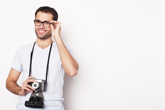 Foto estilo de vida y concepto de personas joven con una cámara retro sobre un fondo blanco