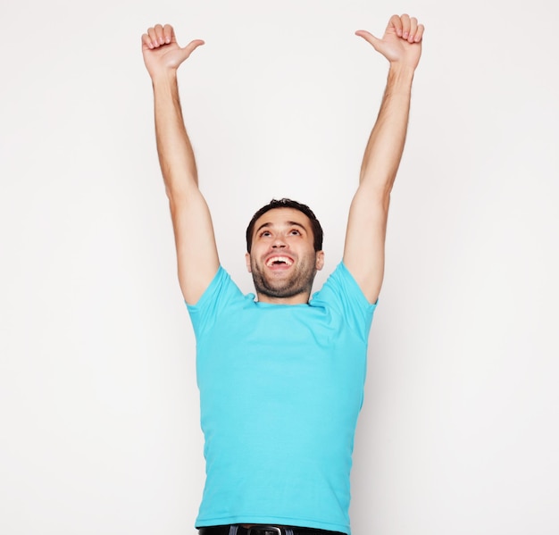 Foto estilo de vida y concepto de personas joven casual en camisa con ambas manos levantadas en el aire ganador y feliz