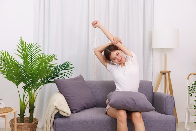 Estilo de vida en el concepto de sala de estar Mujer asiática sentada en el sofá para estirarse para relajarse