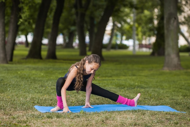 estilo de vida deportivo para niños. yoga al aire libre. niña haciendo ejercicios en el parque