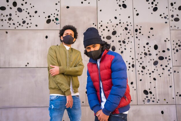 Estilo de vida, dos chicos latinos en una foto urbana con mascarilla.