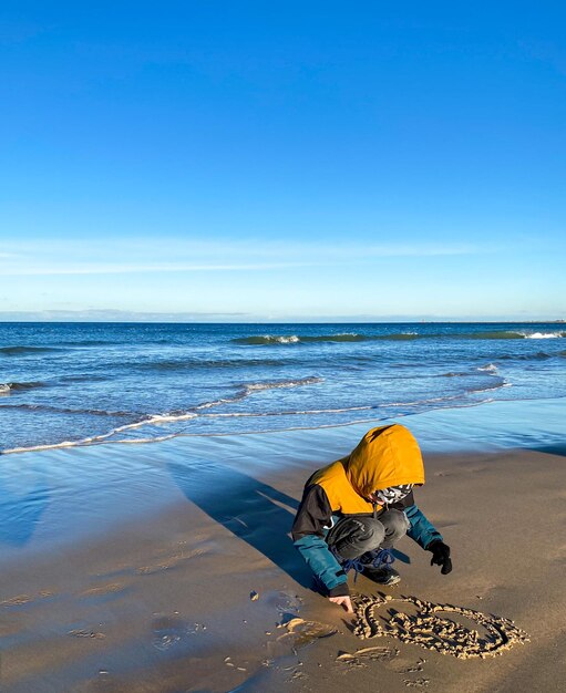 Estilo de vida feliz Un niño camina en un día soleado y frío a lo largo de la orilla del mar