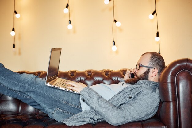 Estilo de vida independiente exitoso hombre con barba logra nuevo objetivo con el portátil en el interior de loft