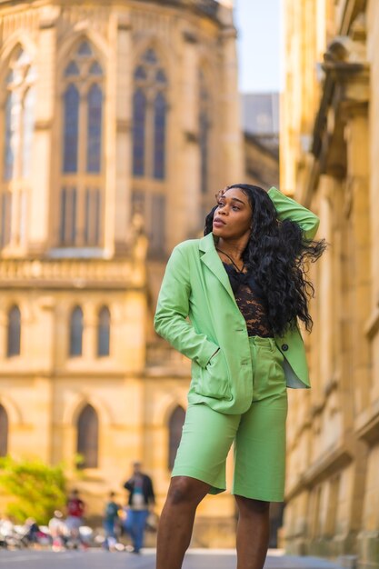 Estilo de vida de una joven de etnia africana negra con un hermoso traje verde. Turista encaramado en la ciudad caminando junto a una catedral