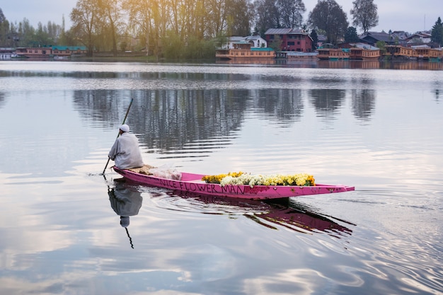 Estilo de vida en el lago Dal, el hombre conduce el bote en medio del lago Dal y la montaña backgrou