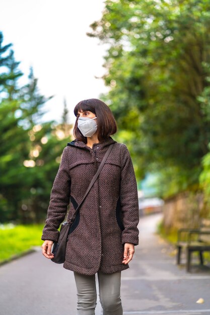 Estilo de vida de una morena caucásica con pelo corto y máscara caminando en un parque. Primeros pasos de la pandemia incontrolada de Covid-19