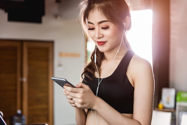 Estilo de vida de mujer joven corriendo cinta de correr usando tecnología de teléfono móvil inteligente ejercicio cardiovascular en el gimnasio