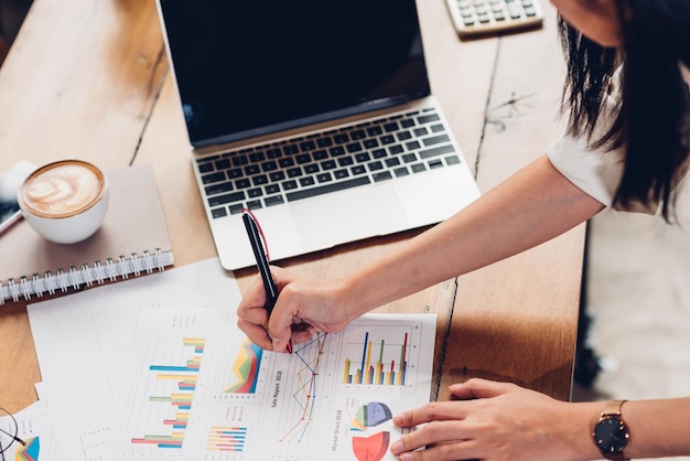 Estilo de vida de las mujeres de negocios trabajando de manera independiente usando una computadora portátil y examinando el documento de ganancias gráficas en la cafetería de loft, las mujeres de negocios miran las estadísticas financieras, el análisis de datos, el gráfico, el crecimiento de las ganancias