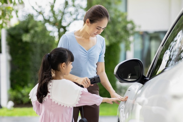 Estilo de vida progresivo de madre e hija con coche EV y estación de carga