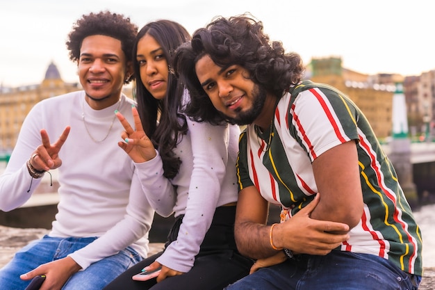 Estilo de vida, retrato de tres amigos negros divirtiéndose en la ciudad con la puesta de sol de fondo