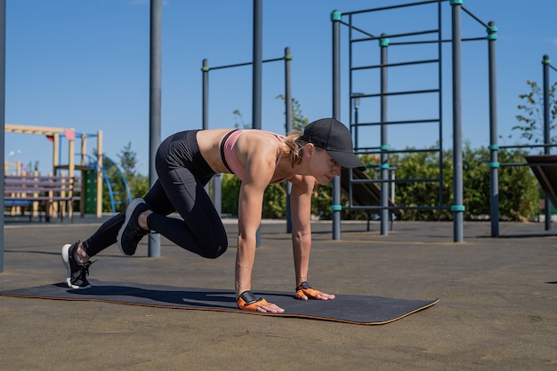 Estilo de vida saludable y activo. Deportes y fitness. Mujer feliz en ropa deportiva trabajando en el campo de deportes en un día soleado de verano, entrenando sus abdominales