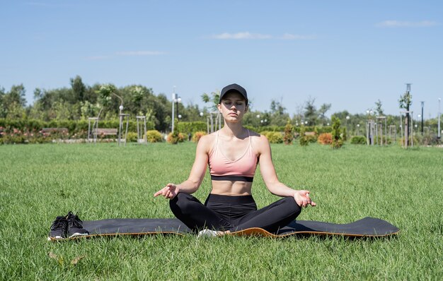 Estilo de vida saludable y activo. Deportes y fitness. Mujer feliz en ropa deportiva trabajando en el parque en un día soleado de verano, meditando